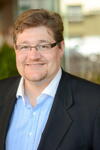 a man wearing a suit and tie smiling and looking at the camera